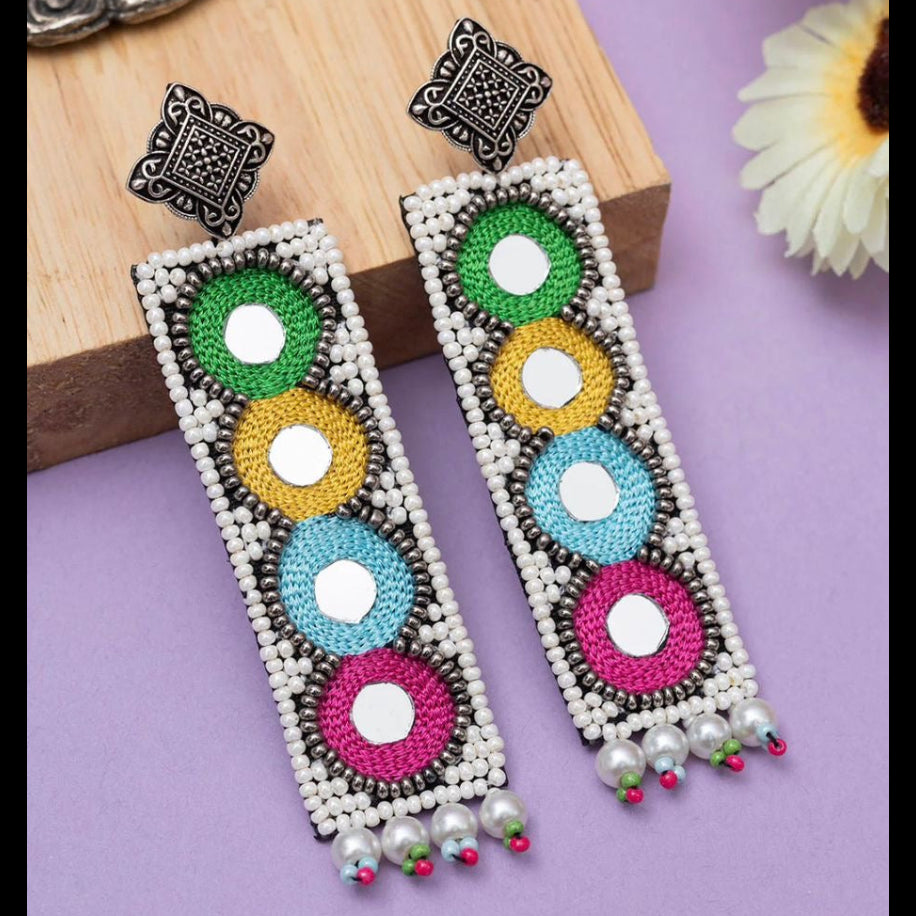 Colorful beaded earrings on a wooden stand with a purple background