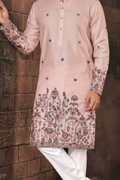 Pink embroidered kurta with white pants against a brown brick wall.