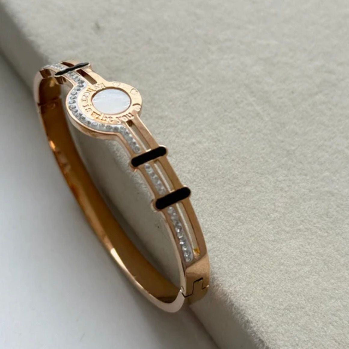 Gold bracelet with a circular design on a light gray background