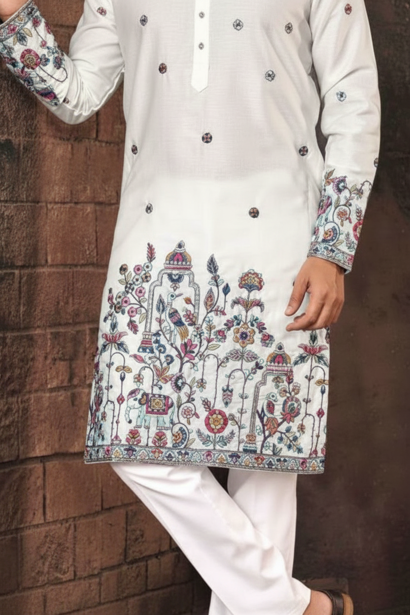 White embroidered kurta with white pants against a brown brick wall.